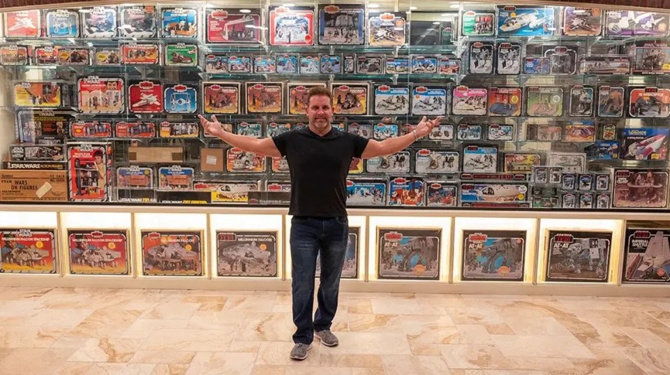 Man standing in front of a large display case filled with vintage Star Wars toys.