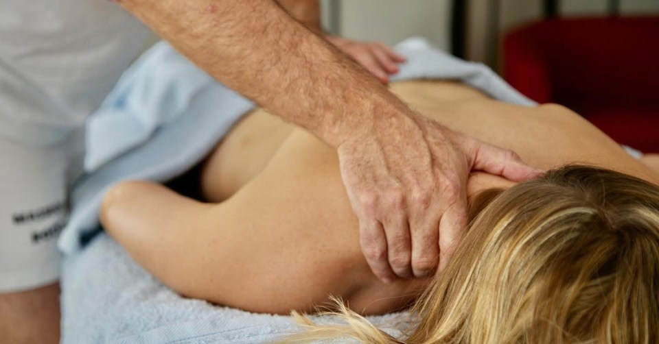 Massage therapist's hands on a woman's back and neck.