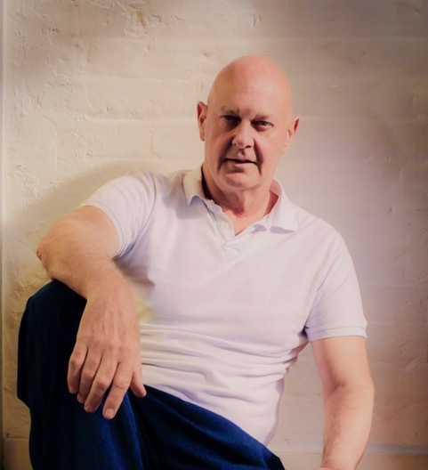 Portrait of a bald man in a white polo shirt.