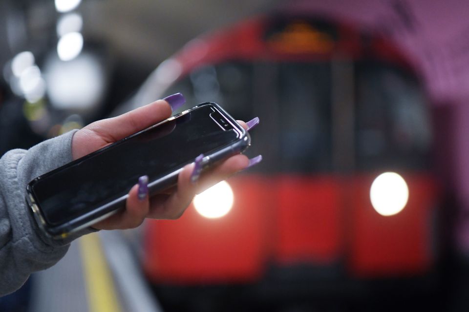 Woman using a phone on a London underground train.