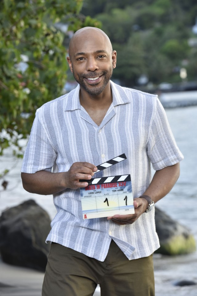 Don Gilet holding a clapperboard for Death in Paradise.