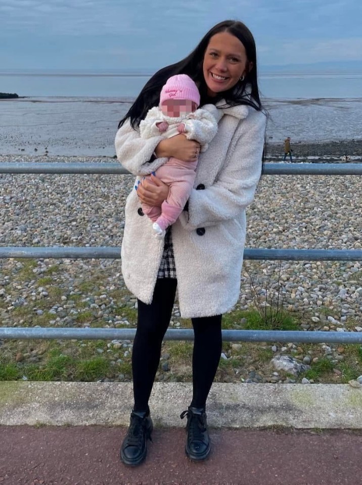 Photo of Kiena Dawes holding her baby daughter near a beach.