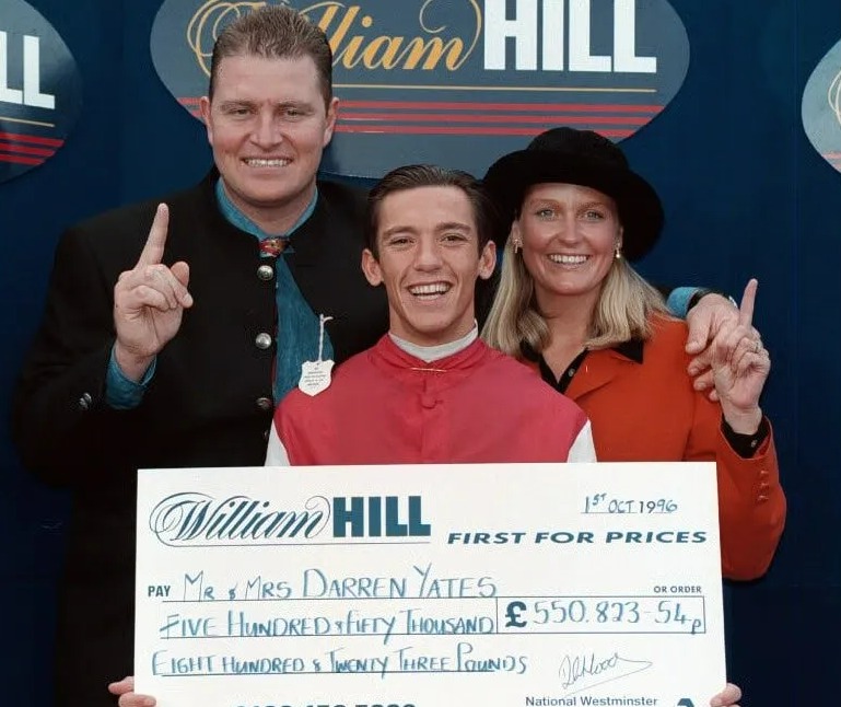 A couple and a jockey holding a large check for £550,823.54.