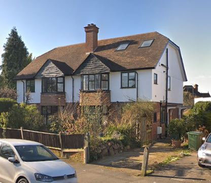 Photo of two properties separated by a hedge.