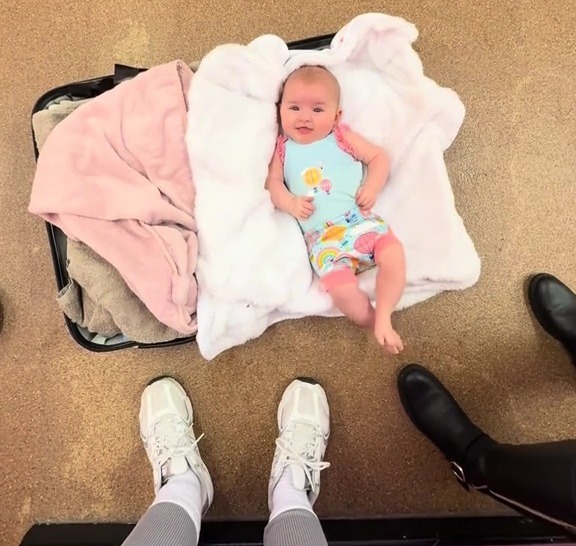 Baby lying on a suitcase used as a changing mat.