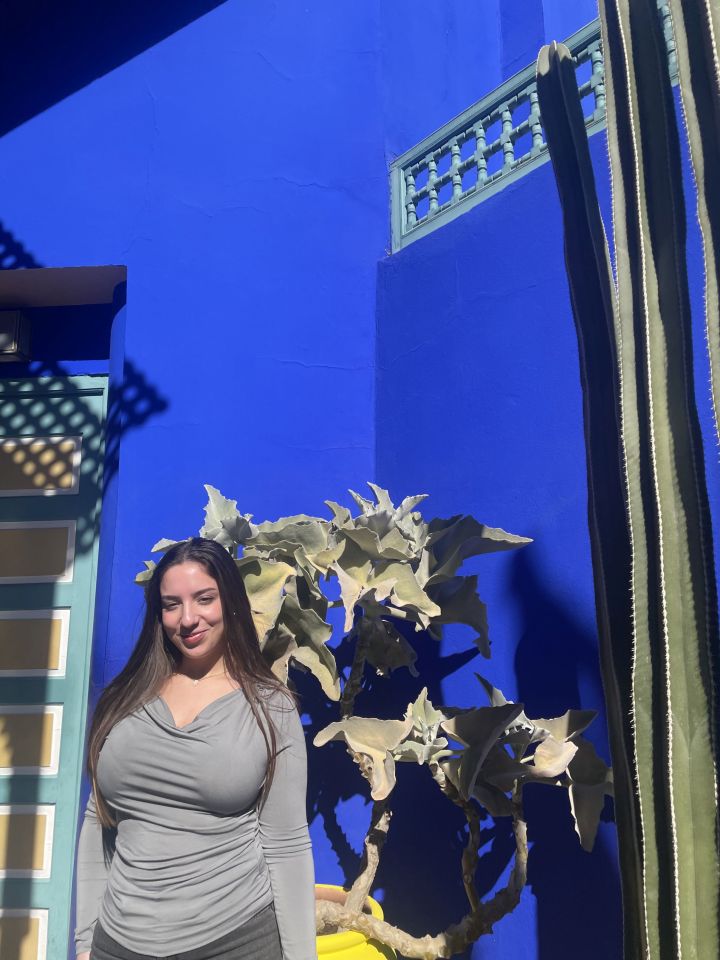 Woman standing in front of a blue wall with plants.