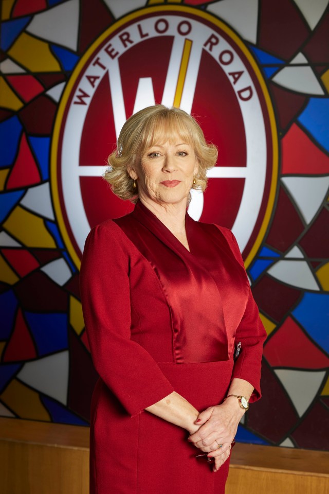 Lindsey Coulson in a red dress, in front of a Waterloo Road logo.