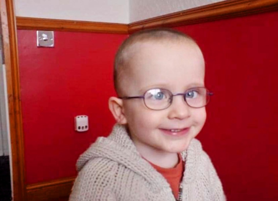 Young boy wearing glasses and a cream-colored sweater.