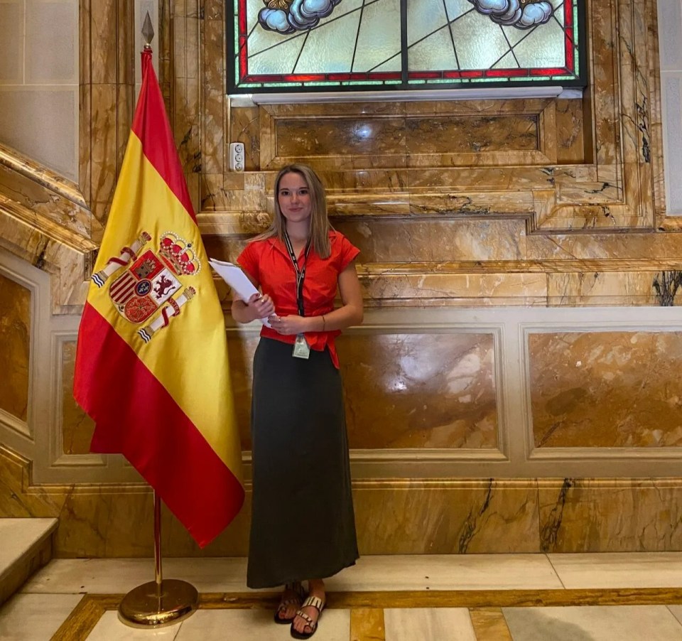 Woman standing in front of Spanish flag.