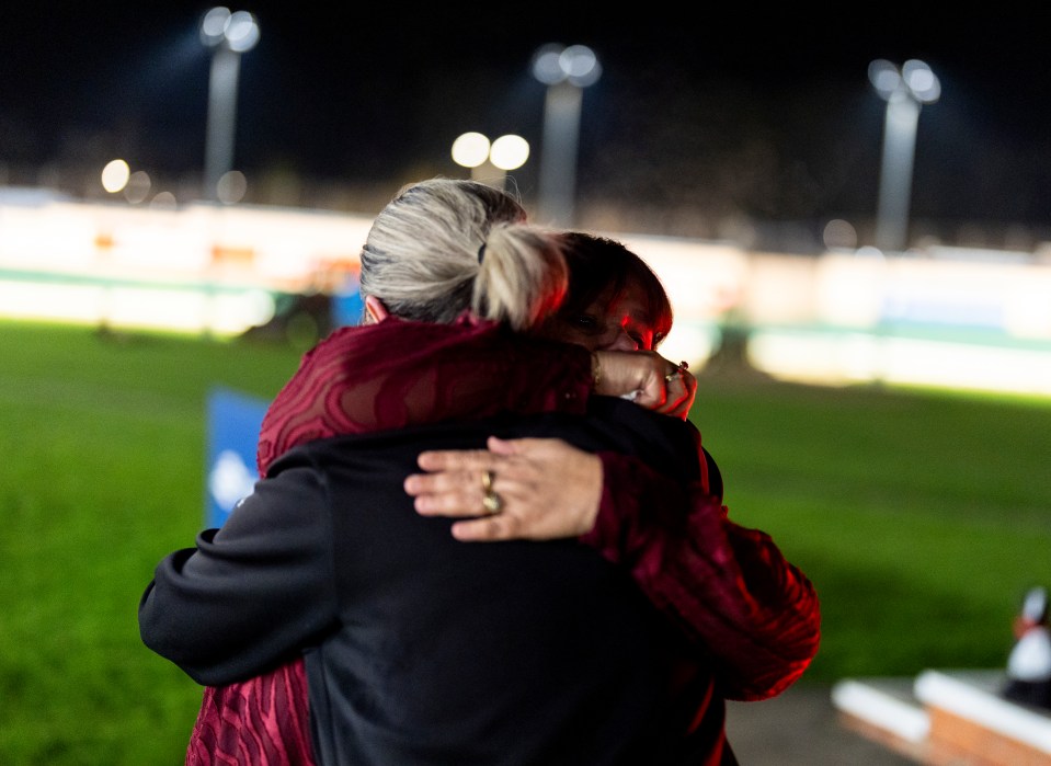 Two women embracing at a greyhound racing stadium after its closing.