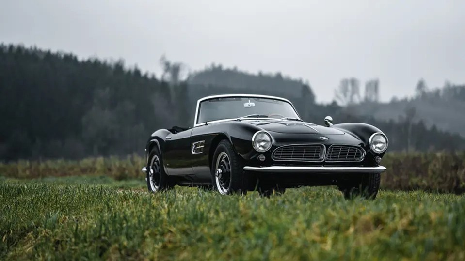 Black 1958 BMW 507 Roadster Series II in a field.