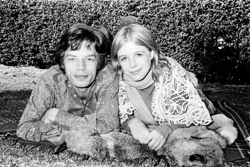 Black and white photo of Mick Jagger and Marianne Faithfull lying on a blanket.