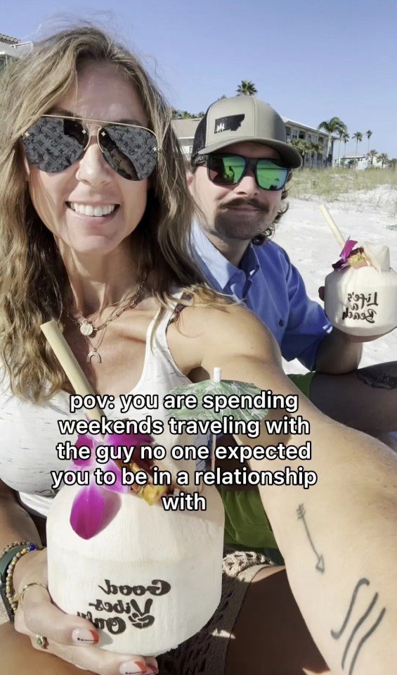 Woman and man on beach holding coconuts; text overlay says they are traveling together unexpectedly.