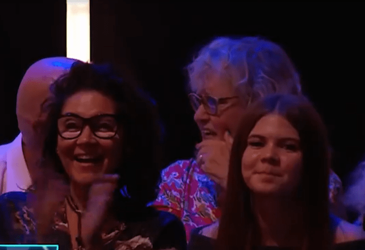 Three women reacting to something, one is laughing and clapping.