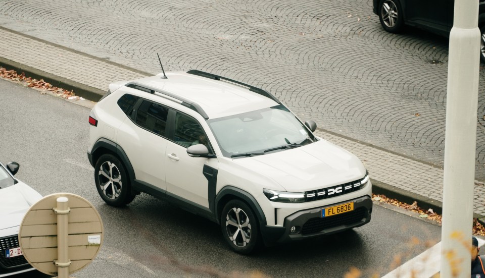 White Dacia Duster driving on a city street.