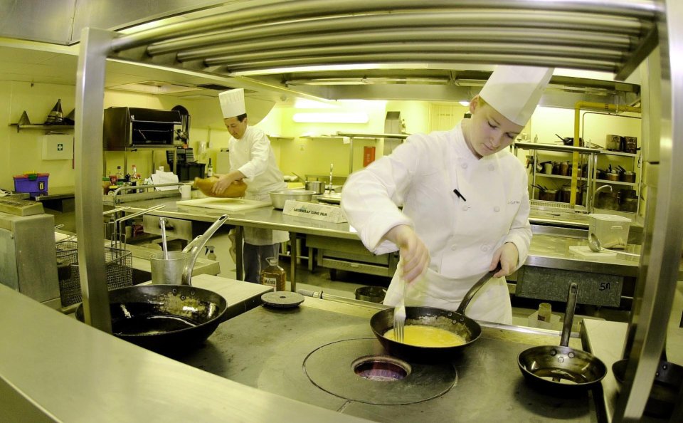 Two chefs in a professional kitchen preparing food.