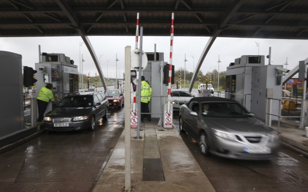 Cars paying tolls at a motorway toll booth.