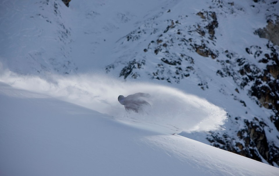 Snowboarder carving through deep snow on a mountainside.