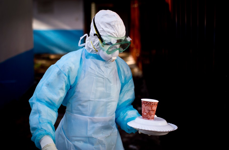 Medical worker in protective gear carrying a meal.