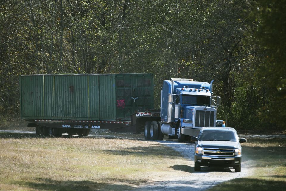 A large shipping container being transported on a flatbed trailer by a semi-truck.