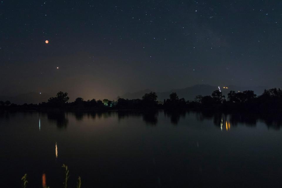 Blood moon and Mars reflected in a lake at night.