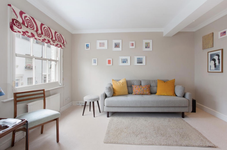 Photo of a living room with a gray sofa, patterned pillows, and framed artwork on the walls.