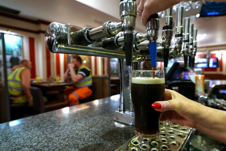 Bartender pouring a pint of Guinness in a pub.