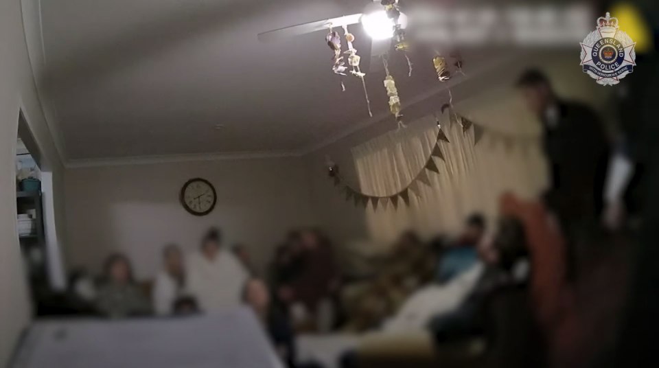 Blurred police footage from inside a home, showing several people.