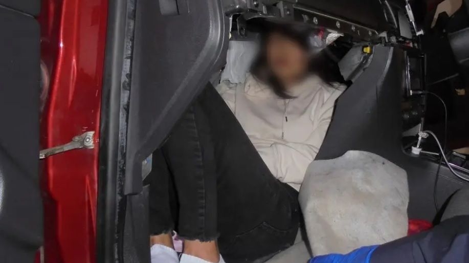 A person hidden in a car's modified compartment.