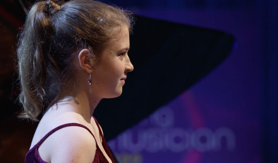 Young woman in profile view, wearing a dark purple dress.