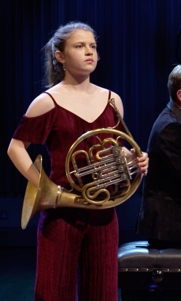 Young woman holding a French horn.