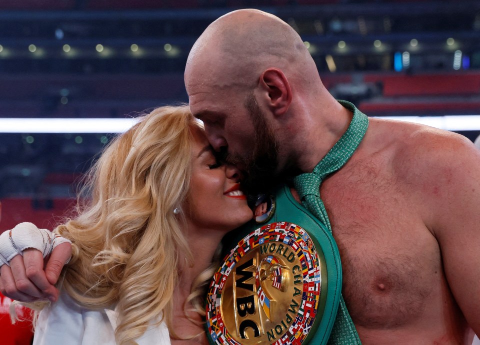 Tyson Fury kissing his wife while holding the WBC World Heavyweight Title belt.