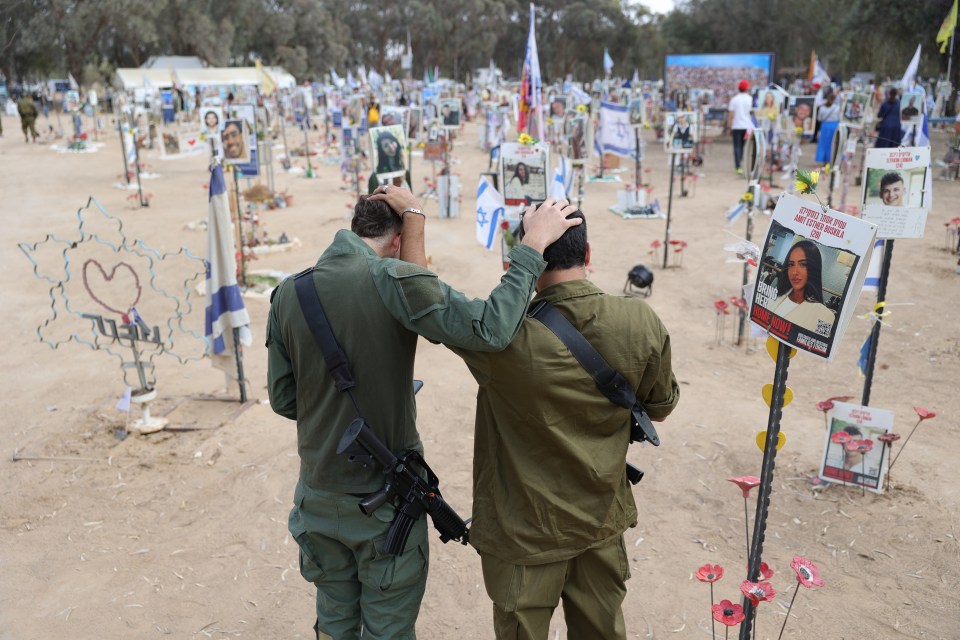 Two Israeli soldiers comfort each other at a memorial for victims of the October 2023 Supernova music festival attack.