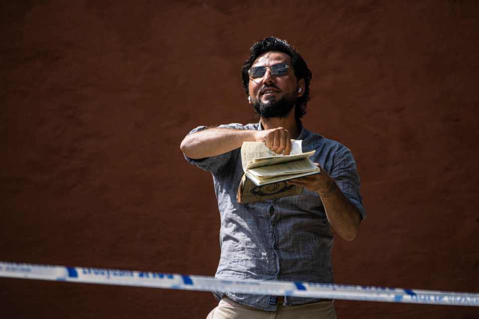 Man holding a book outside a mosque.