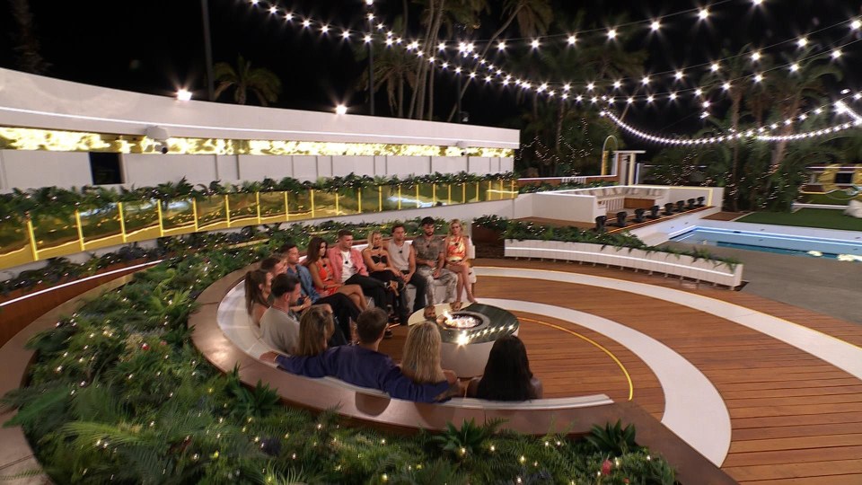 Love Island contestants gathered around a fire pit.