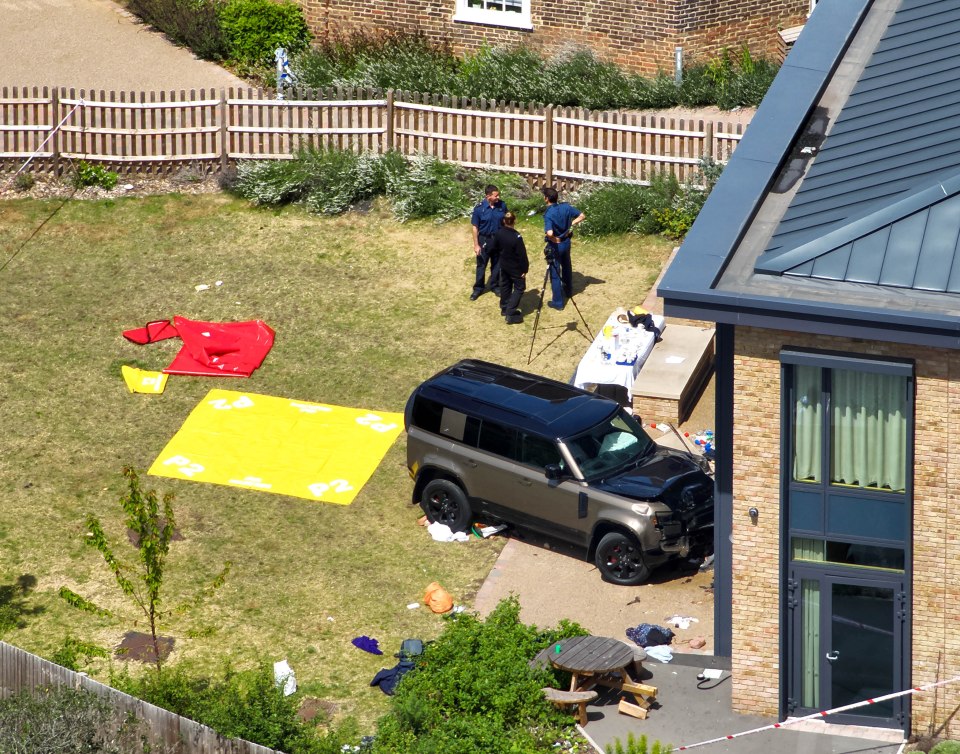 Aerial view of a Land Rover crashed into a fence at a school, with police officers at the scene.