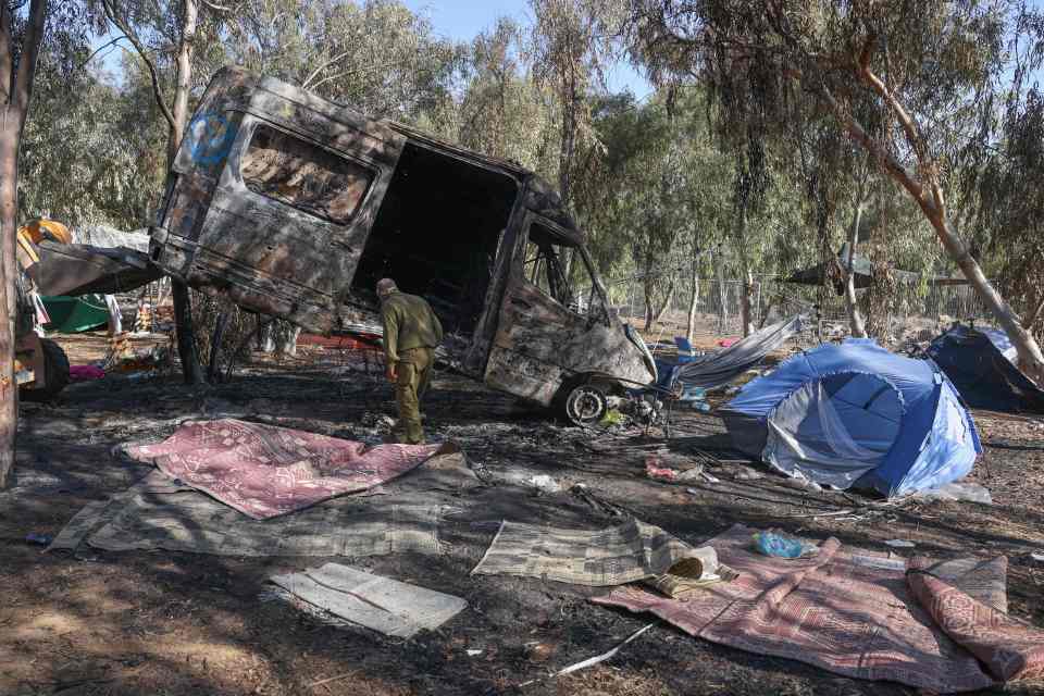 Burnt-out van and tents at a festival site after an attack.