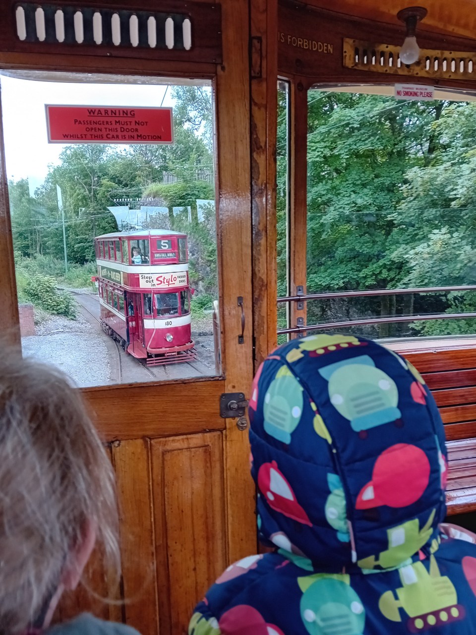 View from inside a vintage tram, showing another tram approaching.