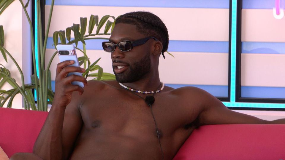 Josh Oyinsan from Love Island looking at his phone.