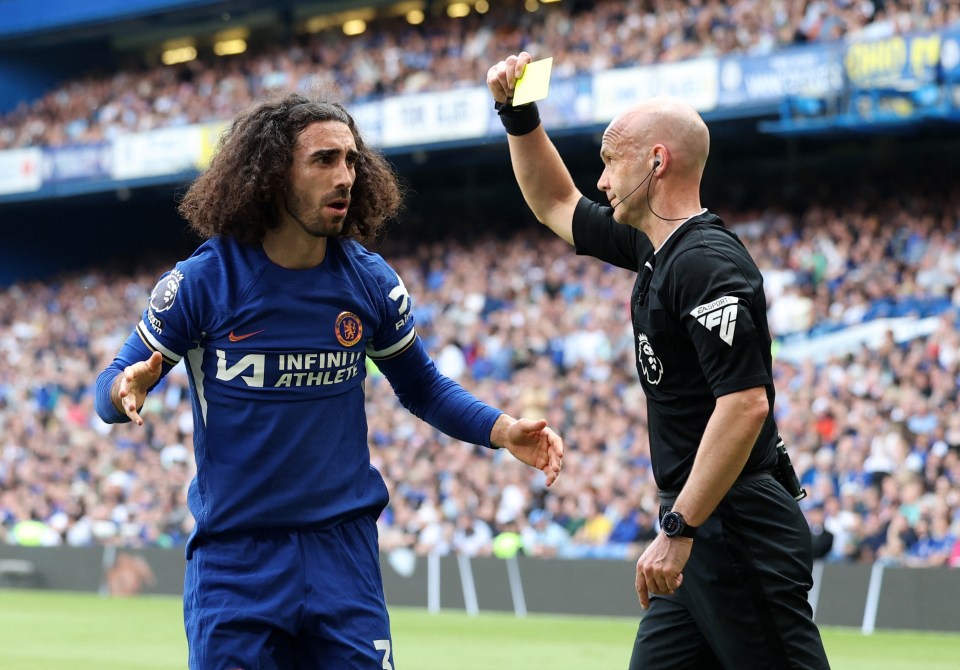 Marc Cucurella receives a yellow card from a referee.