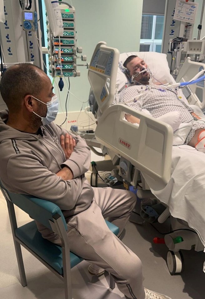 Man sitting beside a man in a hospital bed.