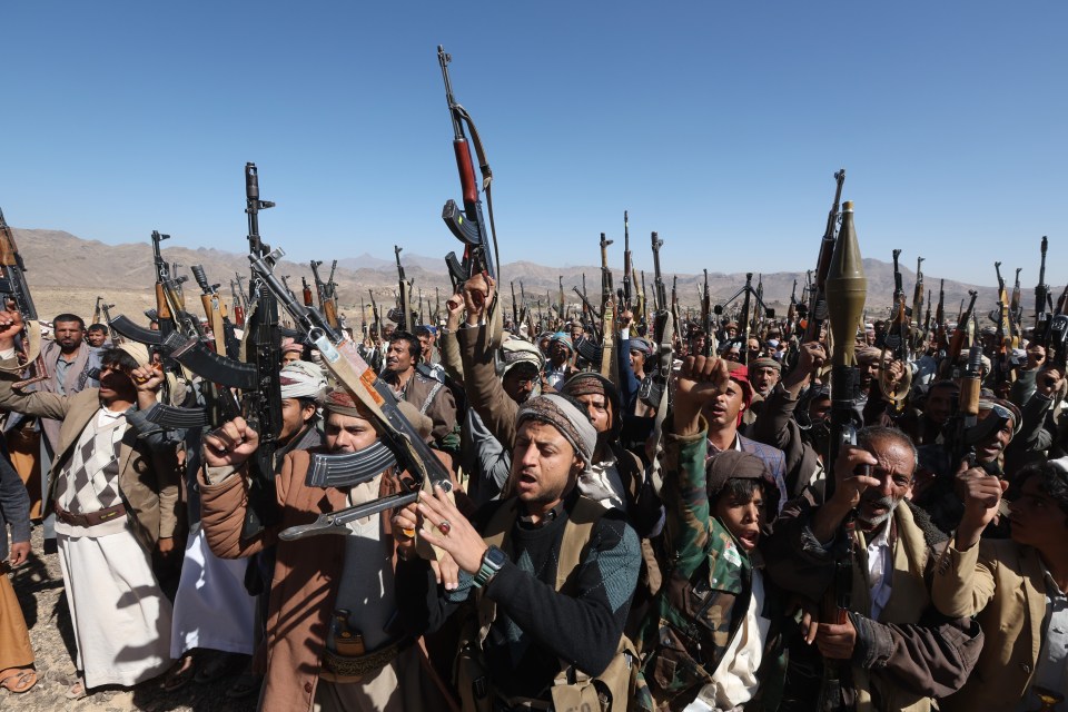 Houthi fighters in Yemen holding weapons aloft.