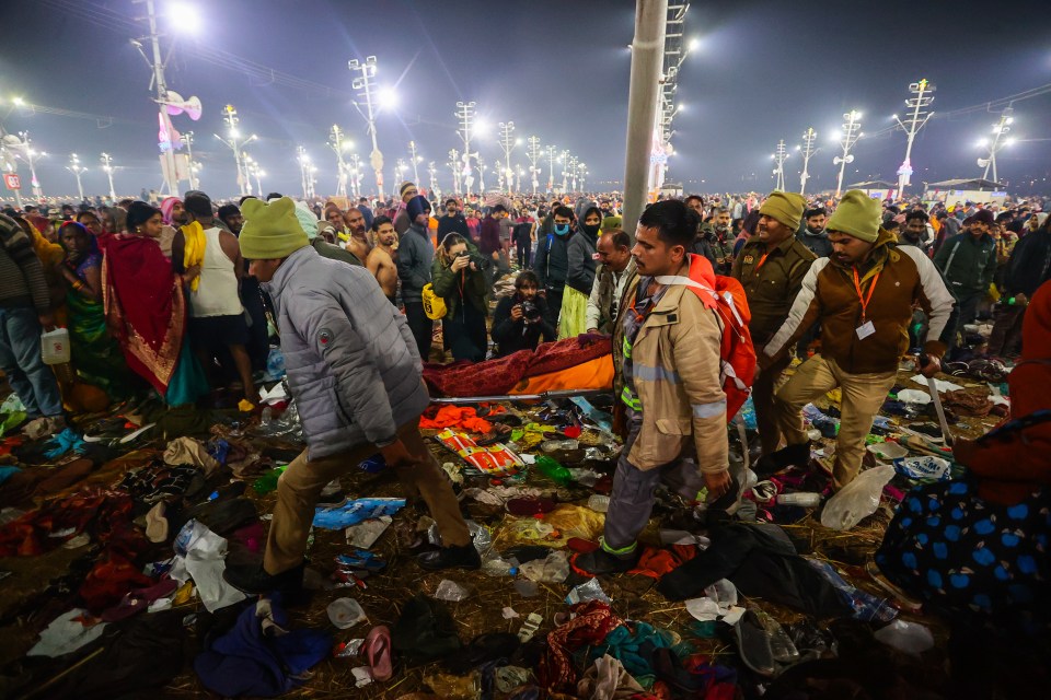 People carrying an injured person through debris at the Kumbh Mela.