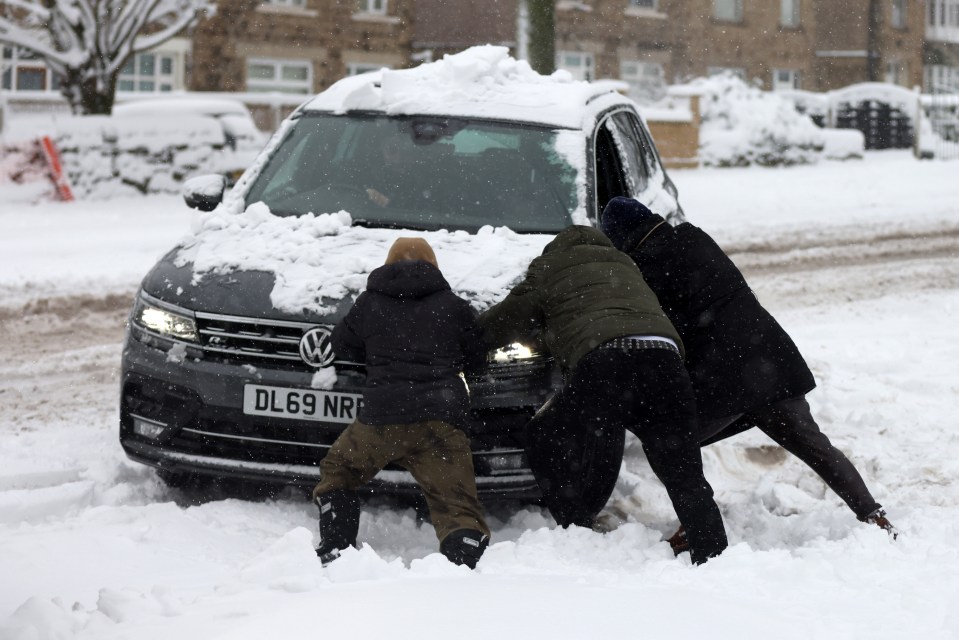 People help push a stranded car  in Bradford