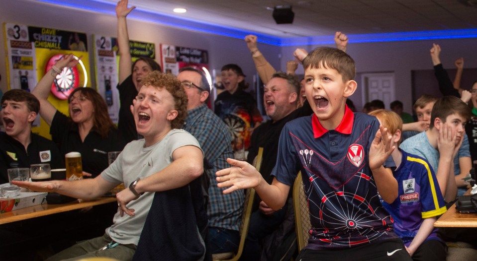 Luke "The Nuke" Littler fans holding supportive signs at a darts academy.