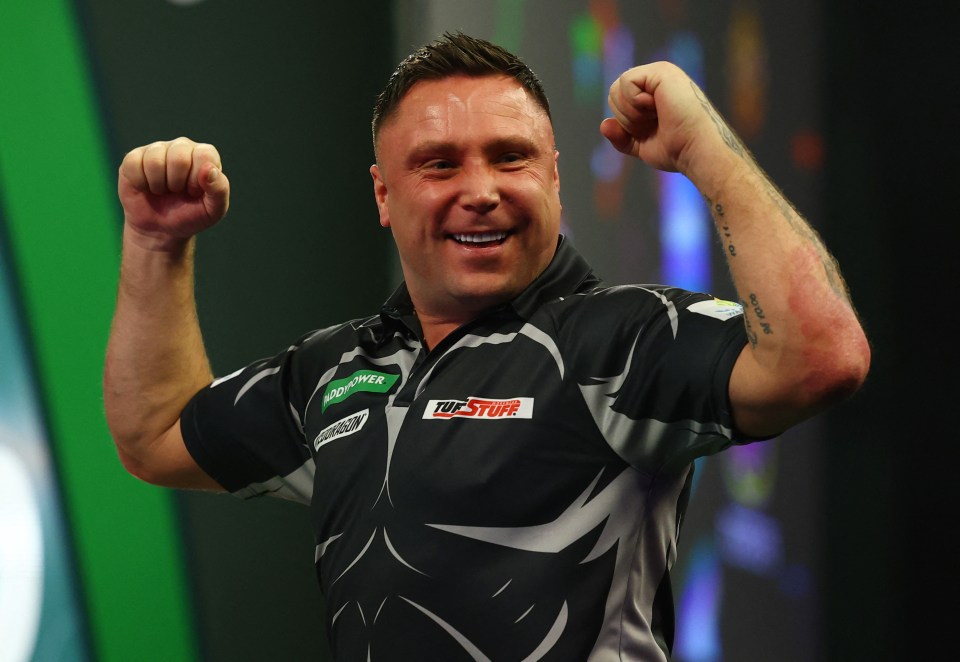 Gerwyn Price celebrates during a darts match.