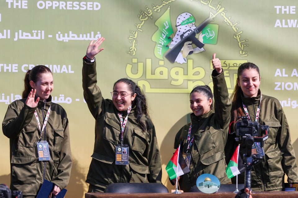 Palestinian fighters and women in military uniforms at a rally.