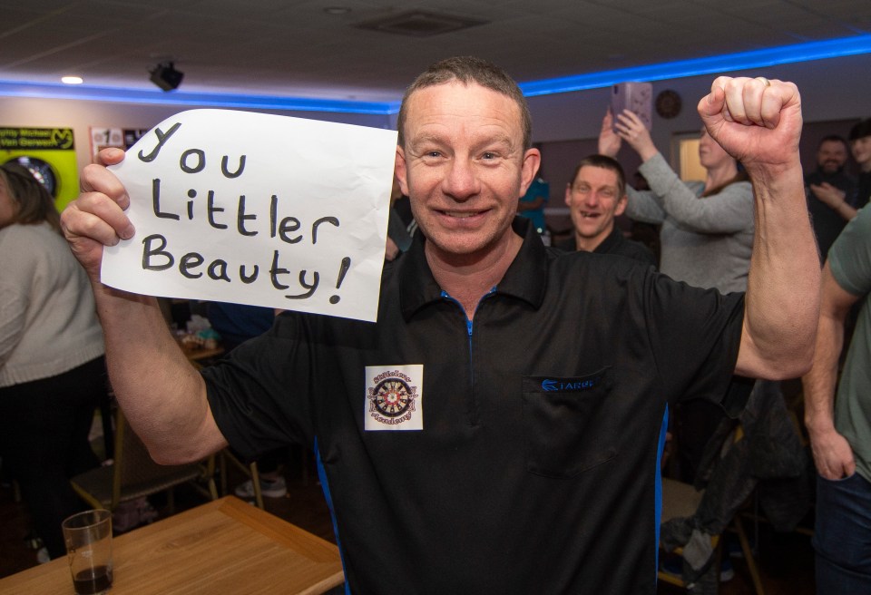 Man holding a sign that says "You Littler Beauty!" and celebrating.