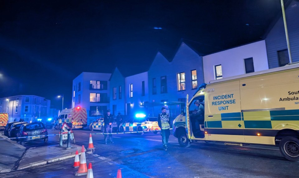 Emergency responders at a nighttime scene in Plymouth, UK.  Police have cordoned off the area following a serious assault.