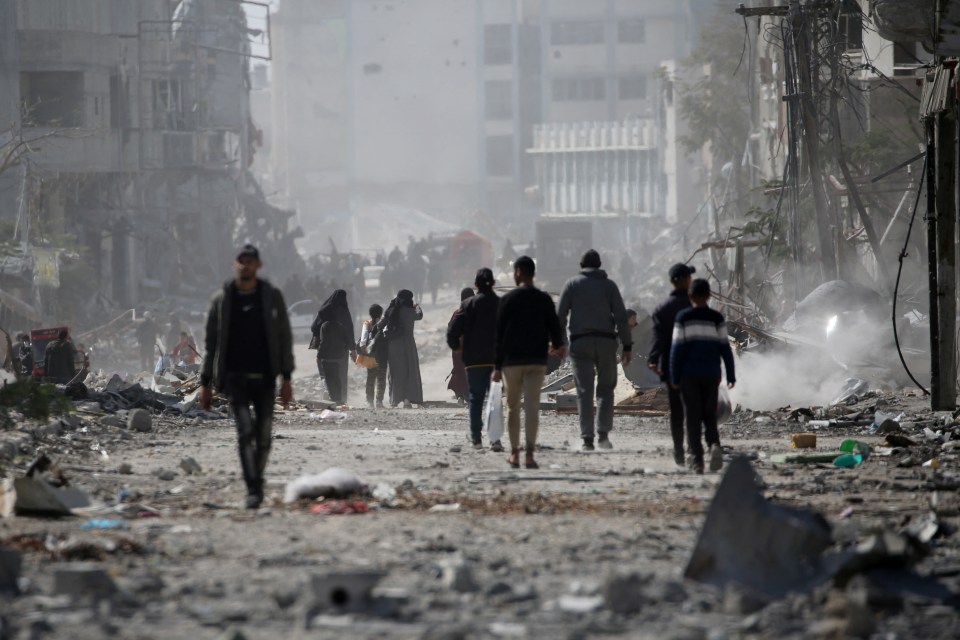 Palestinians walking through rubble in Rafah, Gaza, after a ceasefire.